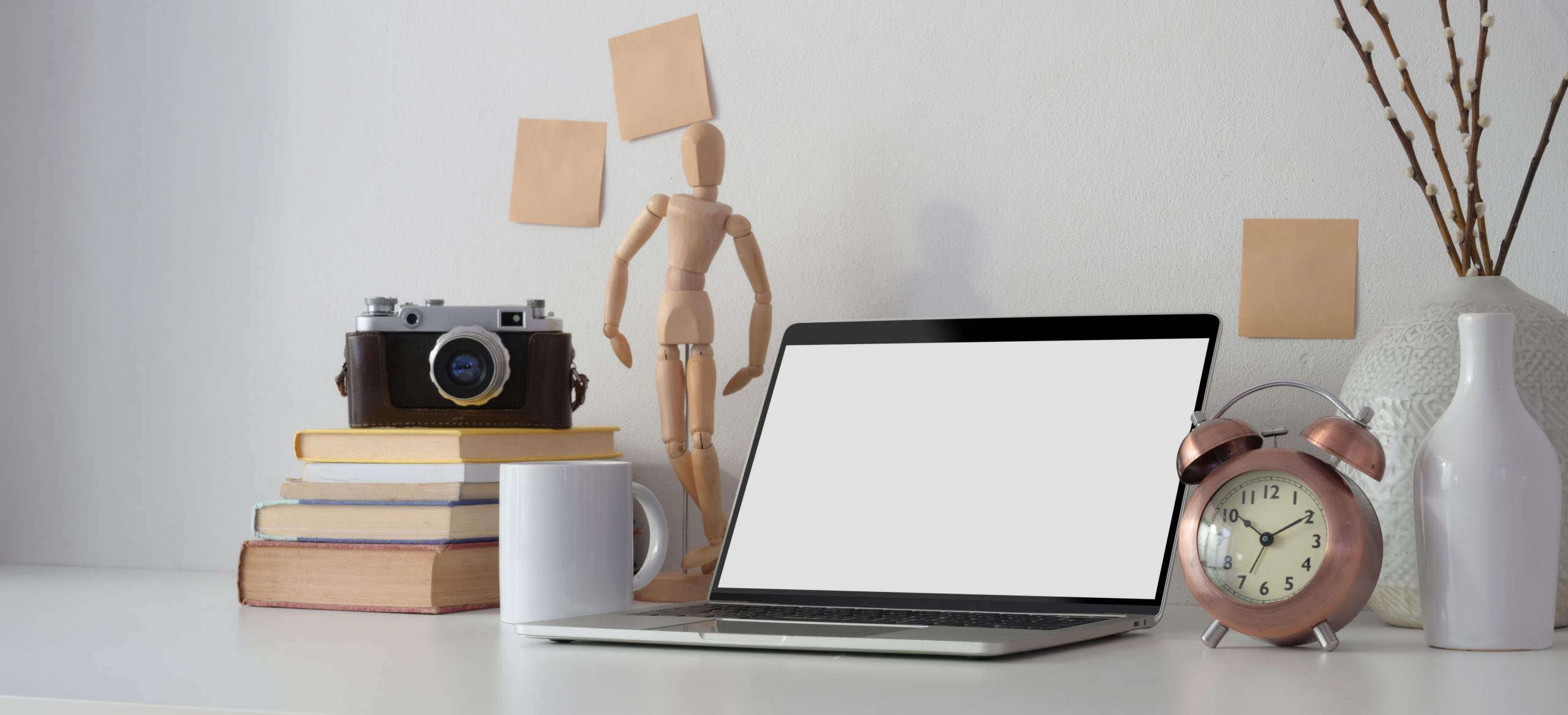 Black and silver laptop computer beside white ceramic mug on white wooden table